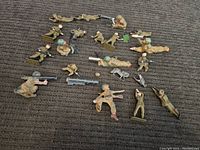 Overview of multiple vintage plastic army men in green and brown colors arranged on dark surface showing poses and condition.