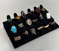 Front angle view showing 20 assorted rings on black ring display stand.