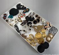 Full view of tray containing multiple pairs of earrings in diverse styles and colors.