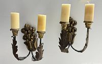 Pair of antique wall candle sconces displayed side by side with faux candles in place, showing front view and decorative details