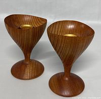 Pair of Mid-Century Modern teak wood candle holders shown front view, displaying wood grain, shape and brass inserts to hold candles.
