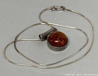 Full view of the necklace and pendant laid flat, showing chain and pendant design.