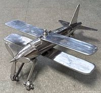 Metallic float plane model with front propeller, biplane wings and dual floats for landing, shown from side and front angles.
