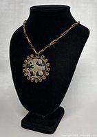 Full view of necklace on black display showing chain and circular pendant with eagle design.