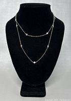 Front view of the long 925 silver necklace on a black jewelry stand showing the multiple bezel-set clear gemstones spaced along the chain.