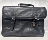 Front view of black leather Danier briefcase with buckles and lock, showing minor wear on surface.