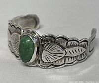 Front angle showing green stone and leaf-stamped details on sterling silver cuff.