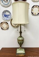 Full view of vintage tall table lamp with light green and brass base and cream fabric shade, shown unlit.