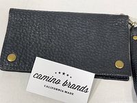 Black textured leather wallet closed with brass snaps visible, accompanied by Camino Brands California Made insert card