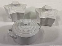 Photo showing all three Le Creuset ramekins: two star-shaped and one traditional round pot shape covered ramekin, white ceramic.