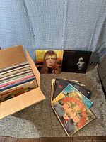 Image showing a cardboard box filled with approximately 60 vinyl records, some records laid out in front including Joan Baez In Concert and Creedence Clearwater Revival albums.