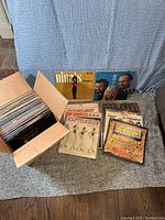 Box containing approximately 60 vinyl records primarily from the 1960s with various artist album covers shown including Nina Simone and The Ventures.