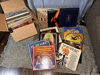 Box with approximately 60 vinyl records inside with various big band and jazz album covers visible.