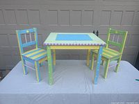 Front view showing the handpainted children’s wooden table and two chairs set with bright colors and decorative stars and stripes