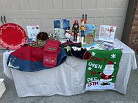 Full view of all items on display on table showing platter, tree skirt, books, Nutcracker figures, snowman, beaded garland and small house figurines