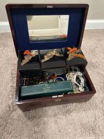 Open wooden Japanese music and jewelry box showing three small lacquered boxes inside with bird design on top and assorted jewelry in compartments below.