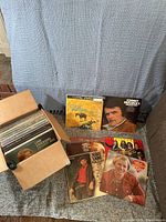 Box containing approximately 50 older country vinyl records and showing several visible album covers including Johnny Paycheck, Frankie Laine, Oak Ridge Boys, Mel Tillis, and Sons of the Pioneers.