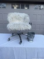 Full view of white faux fur desk swivel chair on metal wheels and decorative metal waste basket