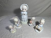 Five Precious Moments figurines displayed together on white backdrop.