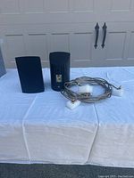 Pair of Definitive Technology ProCinema ProMonitor 80 speakers with attached speaker cables, placed on white cloth.