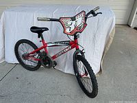 Front side view of the red kids bicycle with number plate "37" on handlebars, showing overall bike condition and design.