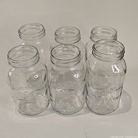 Six clear glass Bernardin mason jars arranged in two rows of three on a flat surface, viewed from above at an angle.