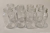 Eight clear glass mason jars, front view showing shape and volume markings.