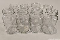 Front view of eight clear glass mason jars arranged in two rows showing size and shape