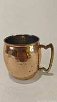 Side view of the hammered copper Moscow Mule mug showing the brass-colored handle and dimpled texture on exterior.