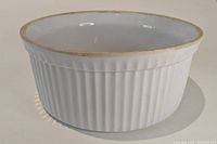 Side angle view showing fluted pattern on the outer surface and rim edge of the porcelian soufflé dish