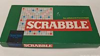 Green Scrabble game box front with title and logo visible, showing this is a German-language edition.