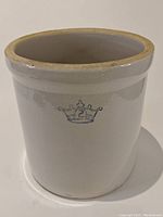 Side view of the vintage stoneware crock showing the 2 crown blue emblem and the overall off-white glaze color.