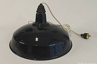 Side view of dark blue enamel pendant lamp with attached white cord and plug