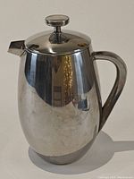 Front view of the stainless steel French press showing body and handle.