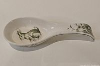 Side view of the ceramic bunny spoon rest showing the bunny illustration and floral handle design.