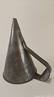 Side view of the old metal funnel showing its conical shape and side handle.