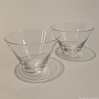 Pair of clear glass martini glasses on white background showing their conical shape.