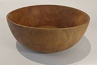 Side view of round wooden salad bowl showing smooth surface and wood grain.