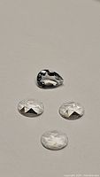 Four faceted natural crystal quartz gemstones: one pear cut and three fancy cut stones shown from a top-down angle on a neutral background