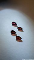 Four pear cut natural garnet gemstones arranged together showing deep red color and clarity.