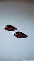 Pair of marquis cut garnet gemstones with deep red orange color and high clarity.