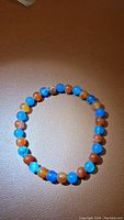 Front view of agate bead bracelet showing mix of blue and red-orange beads with slightly translucent and polished finish.