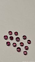 14 round cabochon cut sapphires with deep raspberry red-pink color on a white background showing surface and polish