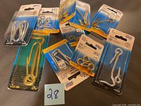 Photo of 10 different metal hooks in original packaging including brass plated, solid brass, and silver hooks from National brand.