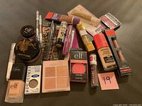 Photo of 19 unopened makeup items including mascaras, foundations, blush, highlighter, lipsticks, brow pencils, and powders.