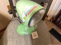 Green novelty Hello Dooney desk lamp angled to show character design and base with switch.