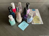 Photo showing eight unopened nail polish bottles in varied colors along with one packaged Sally Hansen Ultimate Shield nail treatment.