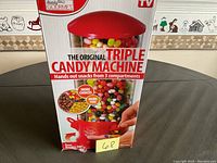 Boxed Handy Gourmet Triple Candy Machine with red lid and clear body showing three compartments with colorful jelly beans and snacks.