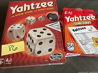 Photo of Yahtzee game box and separate score cards box, both in new condition.