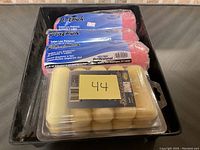 Three pink Veltex Professional paint rollers in original packaging with a pack of four 3-inch foam roller replacements in clamshell packaging placed in a black tray.